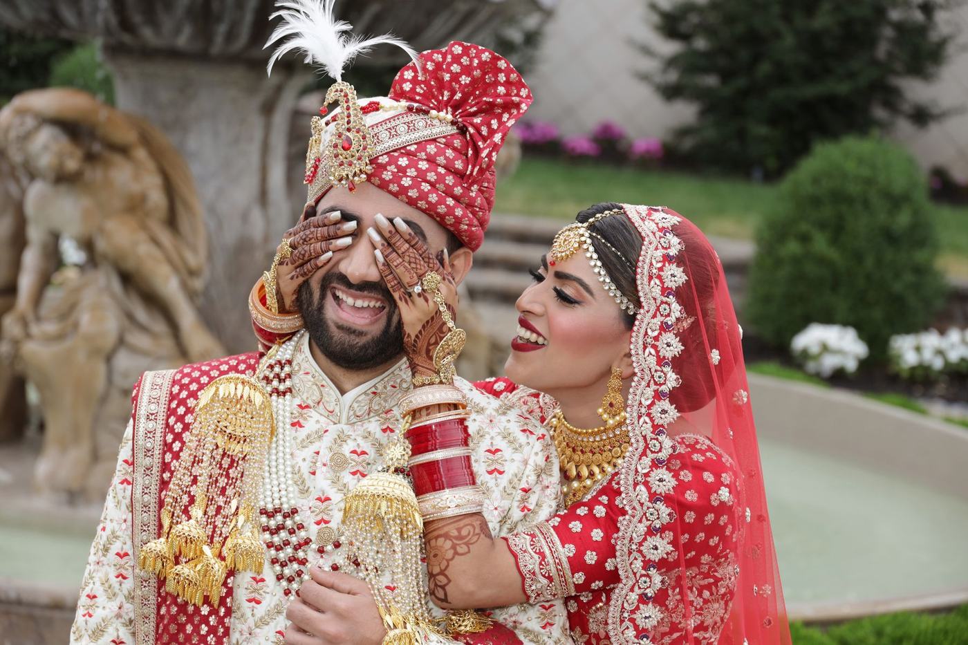 Bride and groom laughing together in red and gold wedding dress