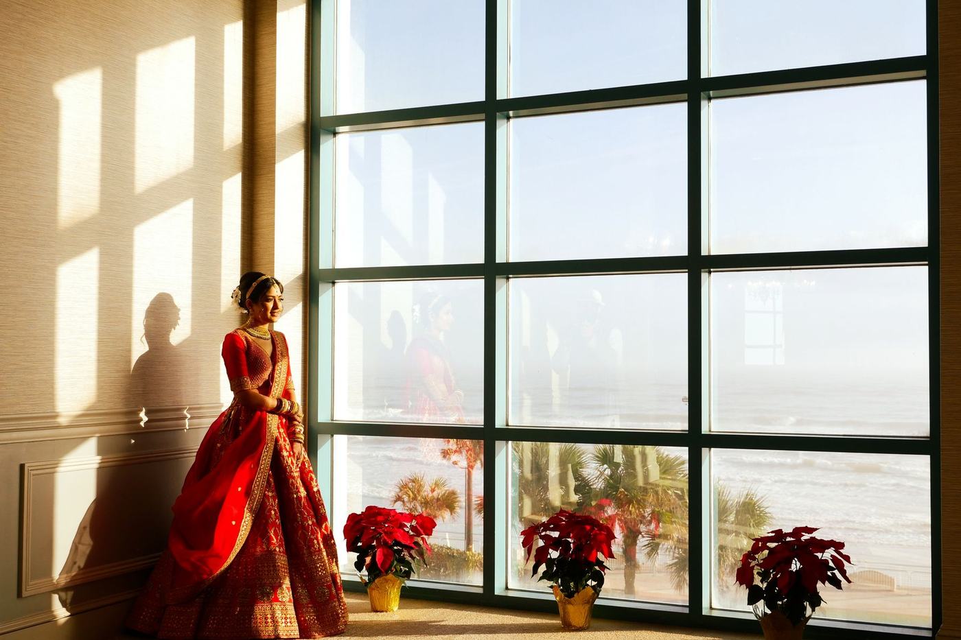 Bride in red at a tall window above the ocean at Daytona Beach