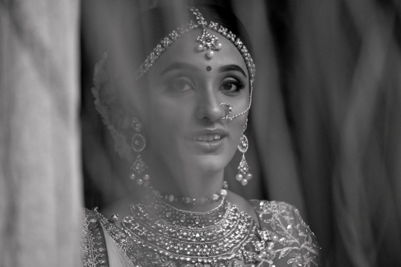 Bride gazing past the camera in her wedding jewels, in black and white