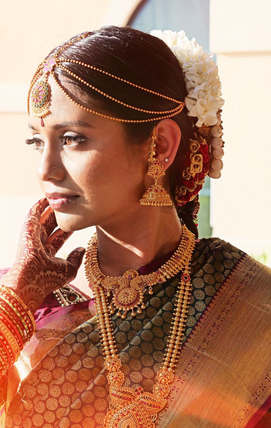 South Indian bride in a gold Kanjivaram sari and temple jewellery looking away