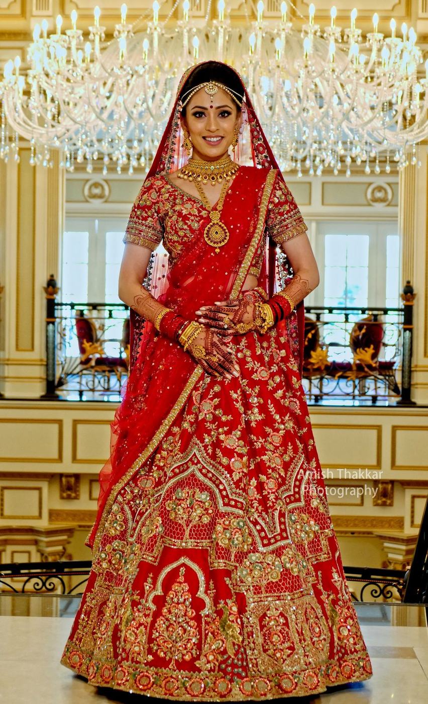 Bride in red and gold on the grand staircase of The Legacy Castle