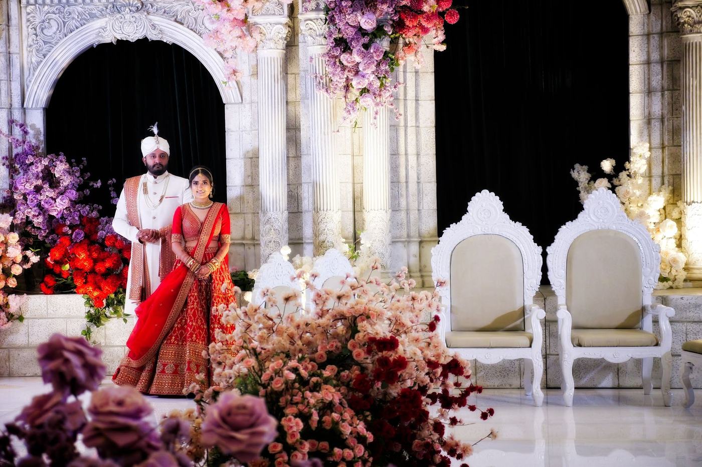 Bride in red on the white reception stage among blush florals