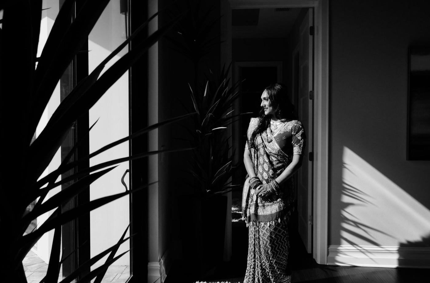 Bride standing in shadow and window light, in black and white