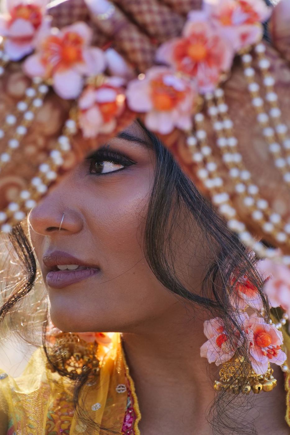 Bride in profile beneath strands of pearls and fresh flowers