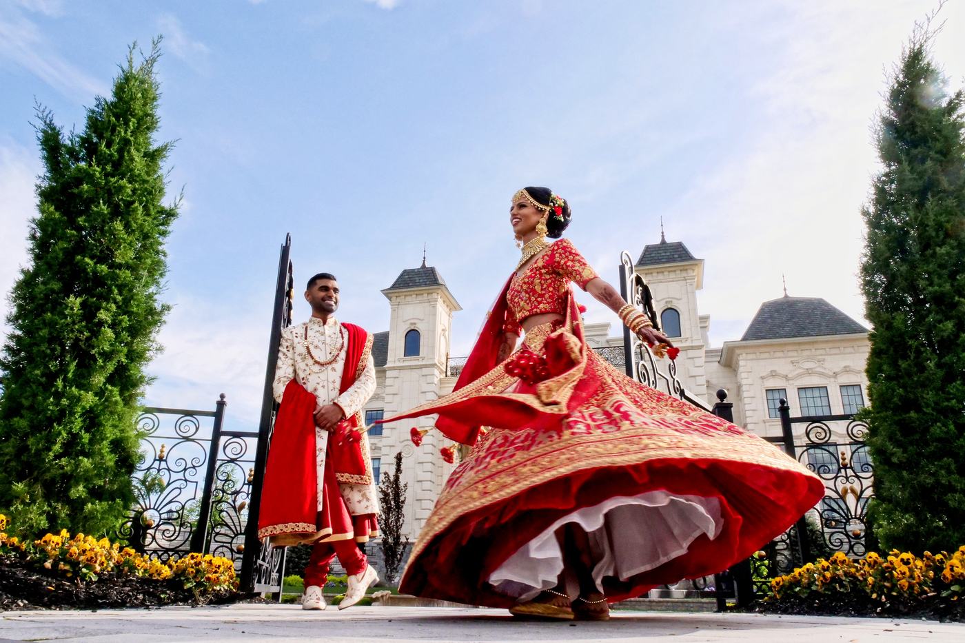 Bride in red twirling at the iron gates of Park Chateau Estate