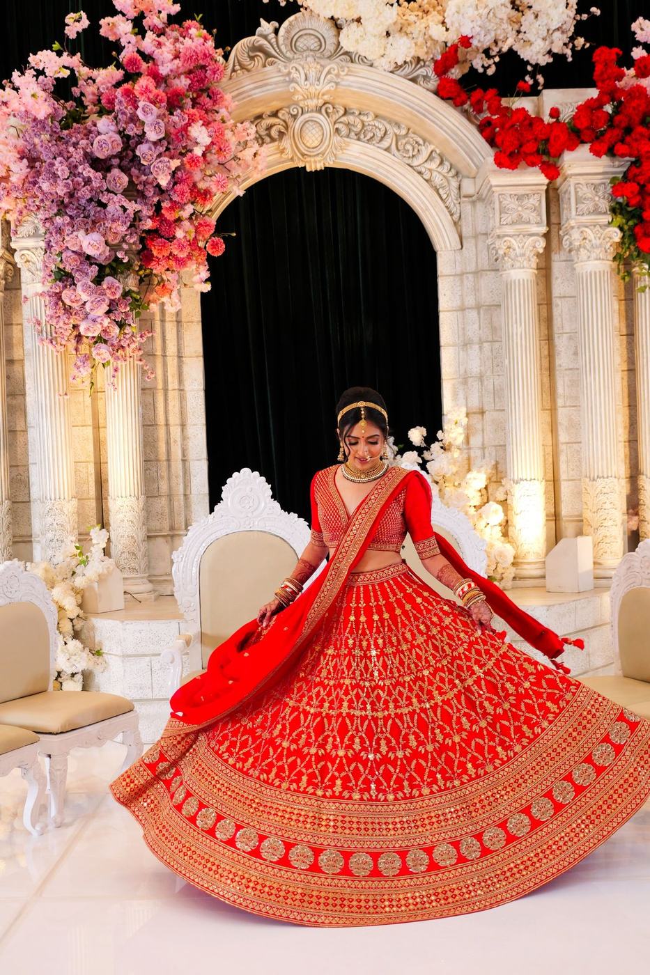 Bride twirling her red lehenga on the reception stage