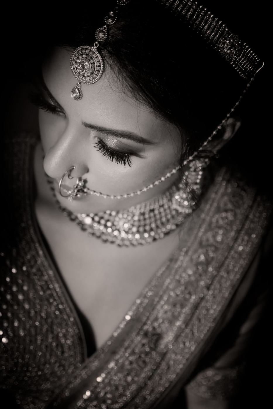 Bride with eyes closed, maang tikka and nose ring, in black and white