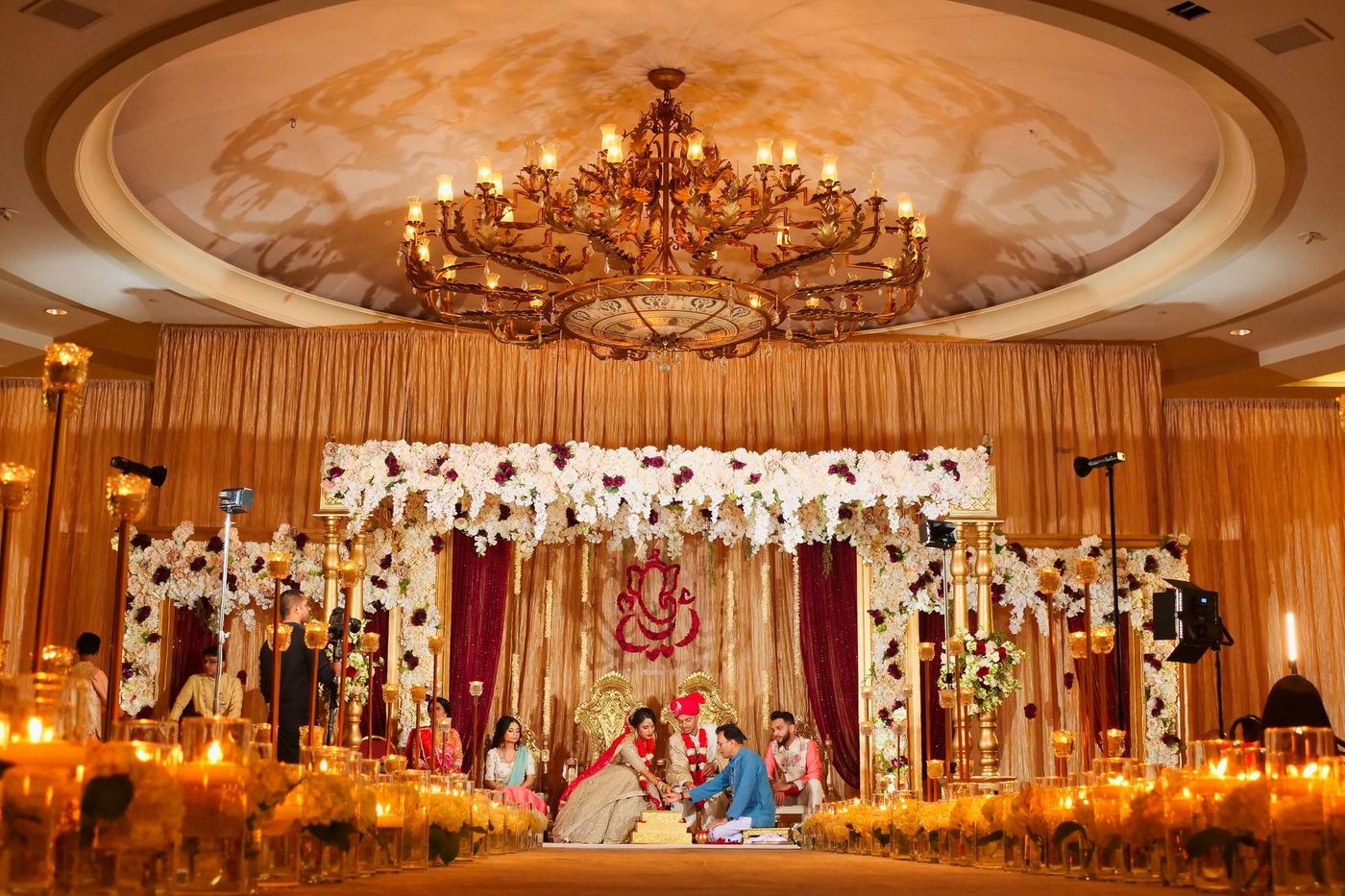Ceremony in the warm glow of a floral mandap and chandelier