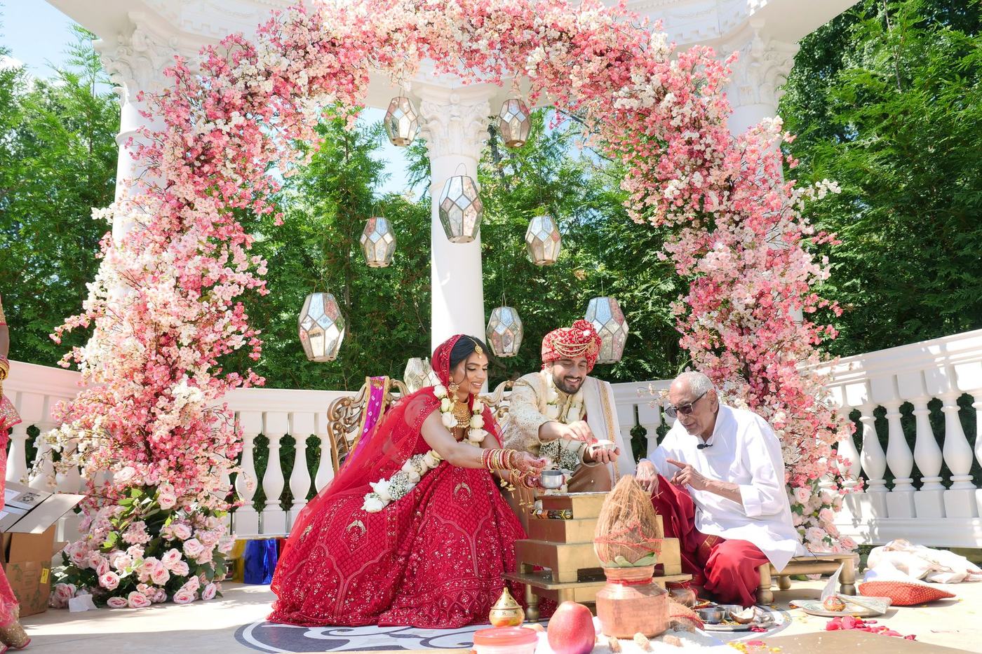 Ceremony under a mandap of pink florals and hanging crystals