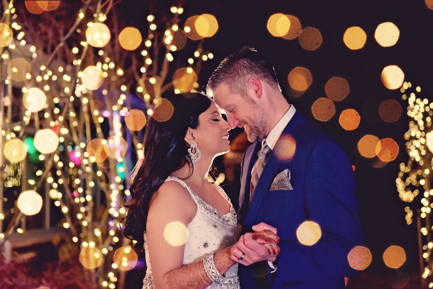 Couple close together among fairy lights at night