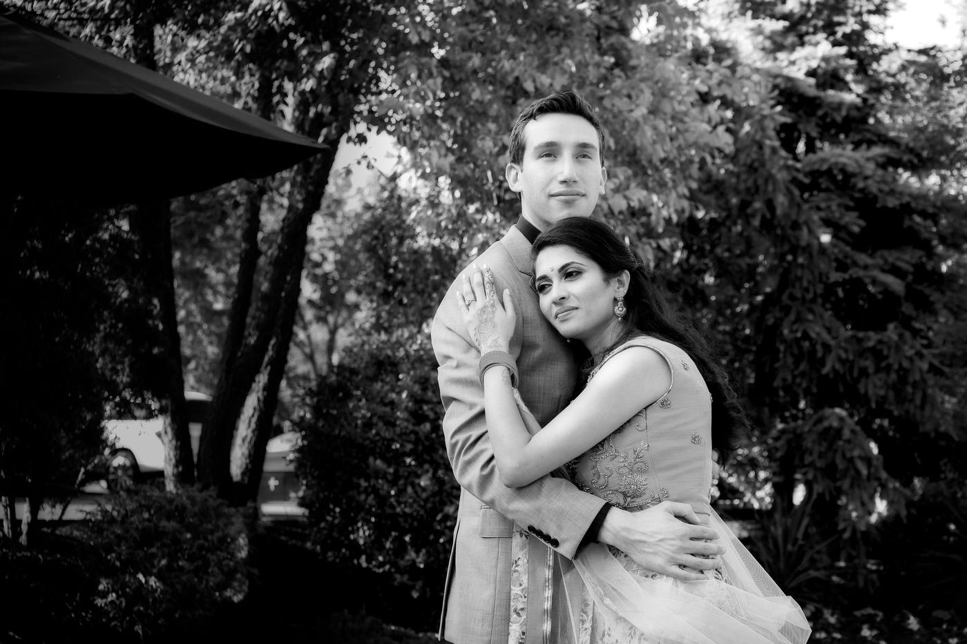 Couple embracing among garden trees, in black and white