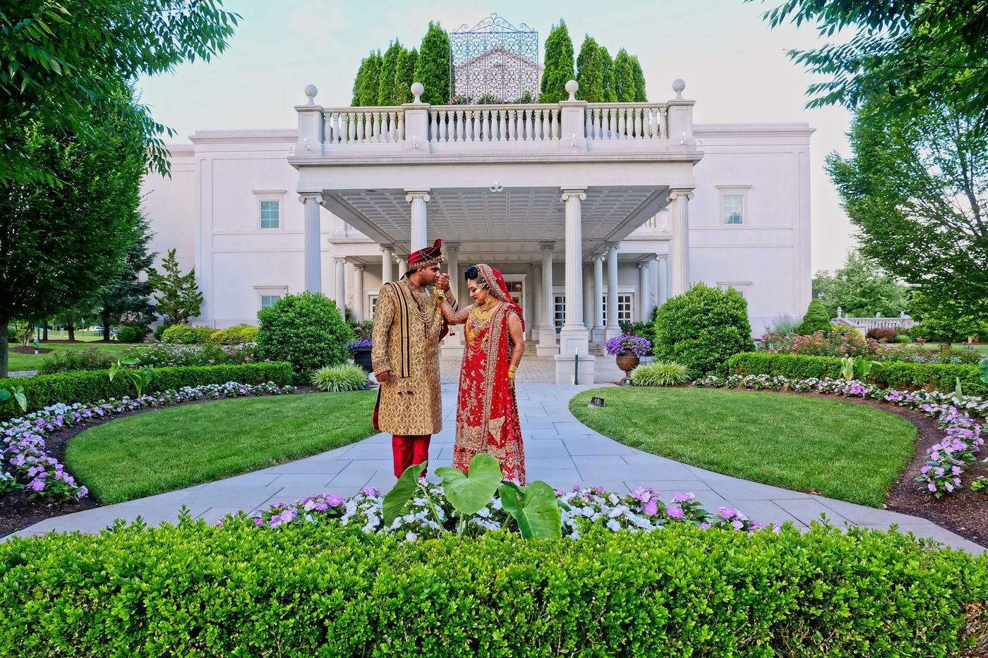Couple in the formal gardens before a white mansion