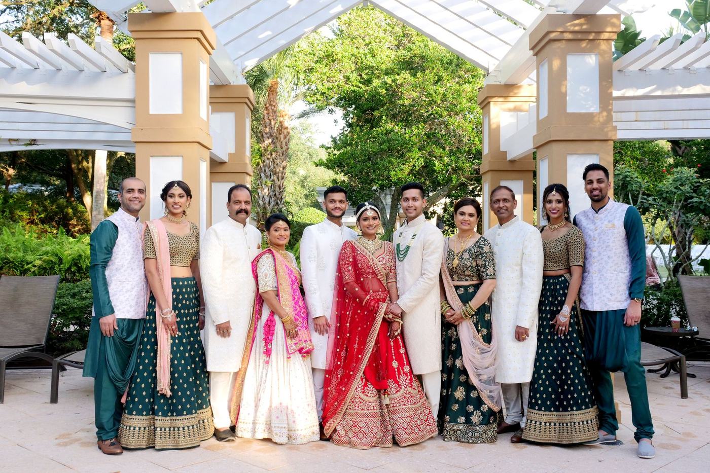 Bride and groom with both families under a garden pergola