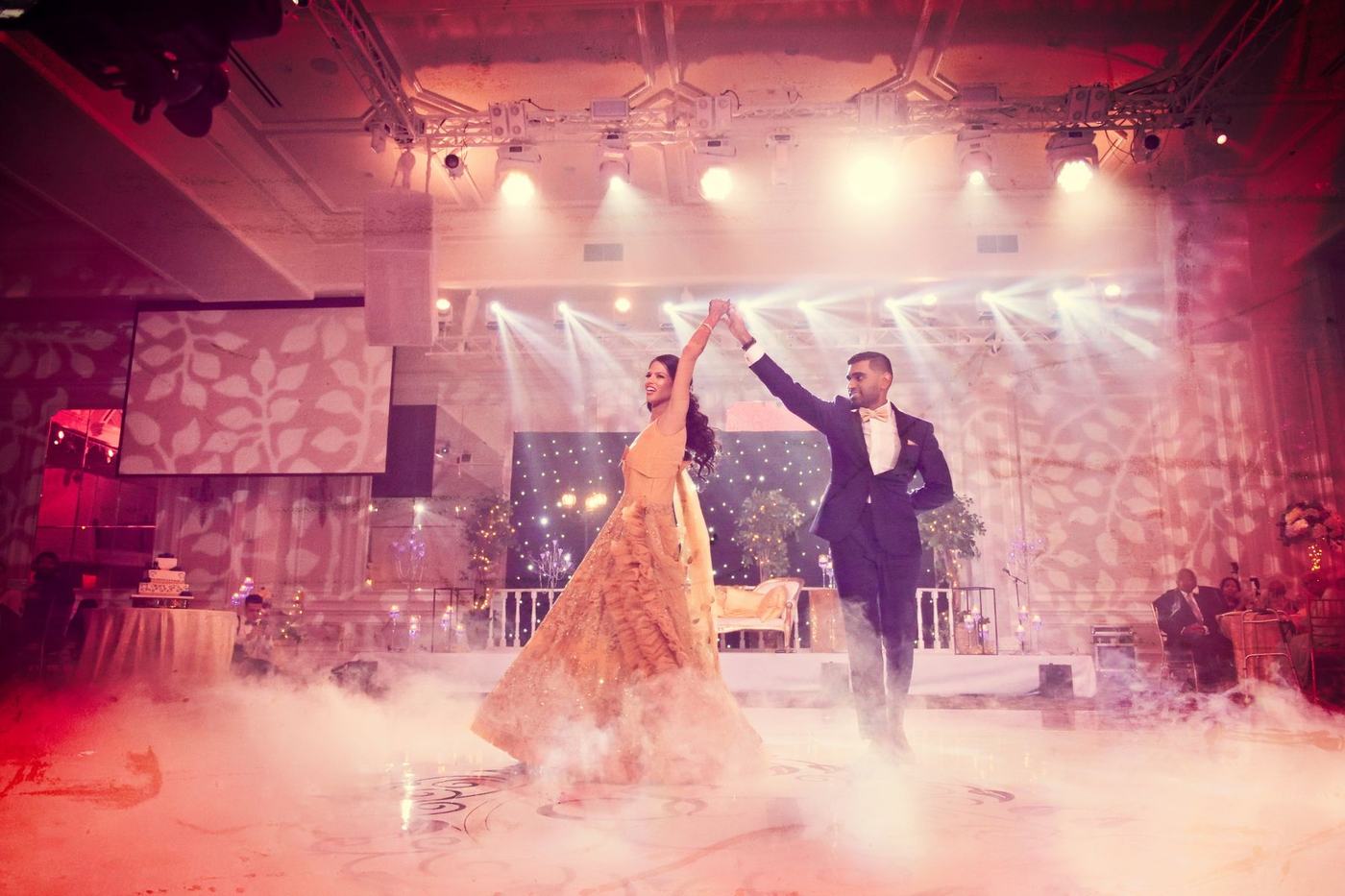 First dance beneath white spotlights on a wide dance floor