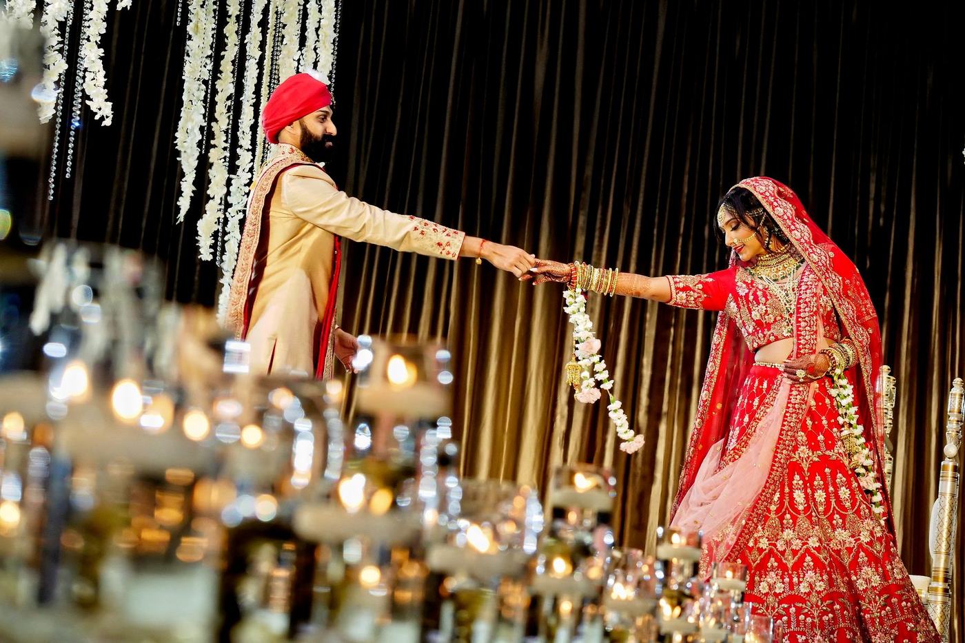 Garland exchange beneath hanging crystals at the mandap