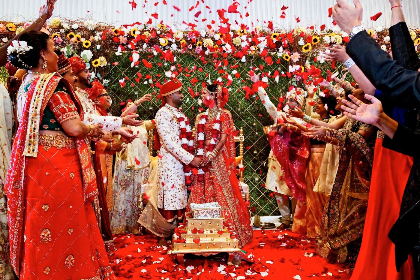 Bride and groom exchanging garlands in a shower of red petals