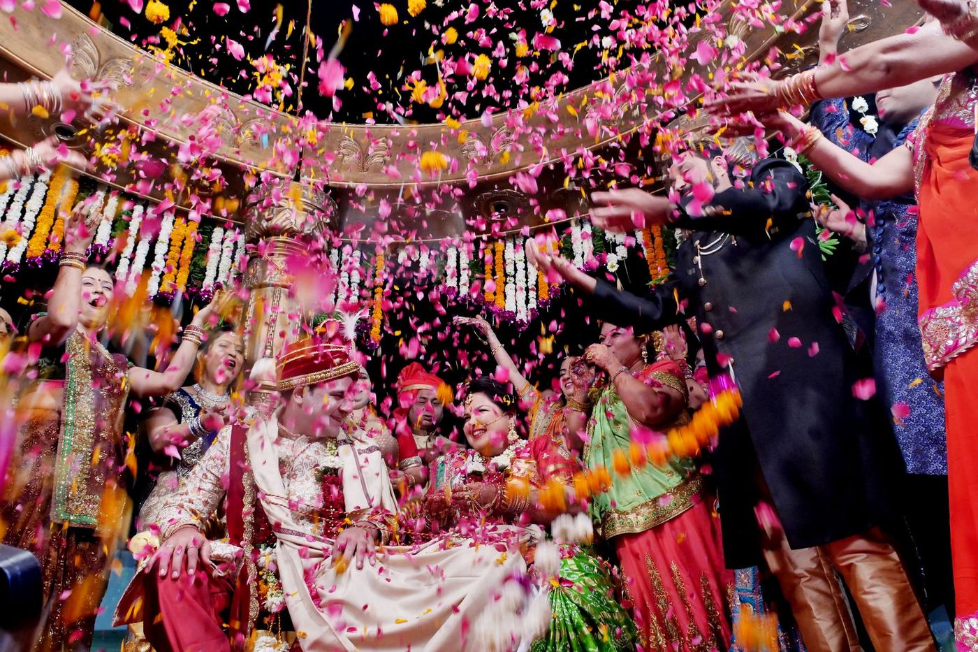Guests throwing petals over the couple at the mandap