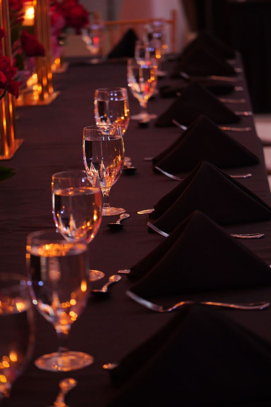 Reception table glassware and black linen in candlelight