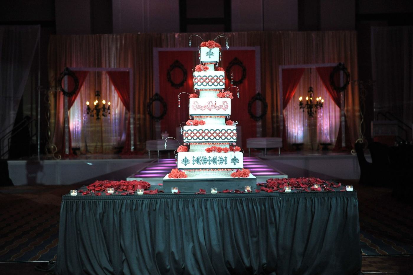 Tiered wedding cake on the red-lit reception stage