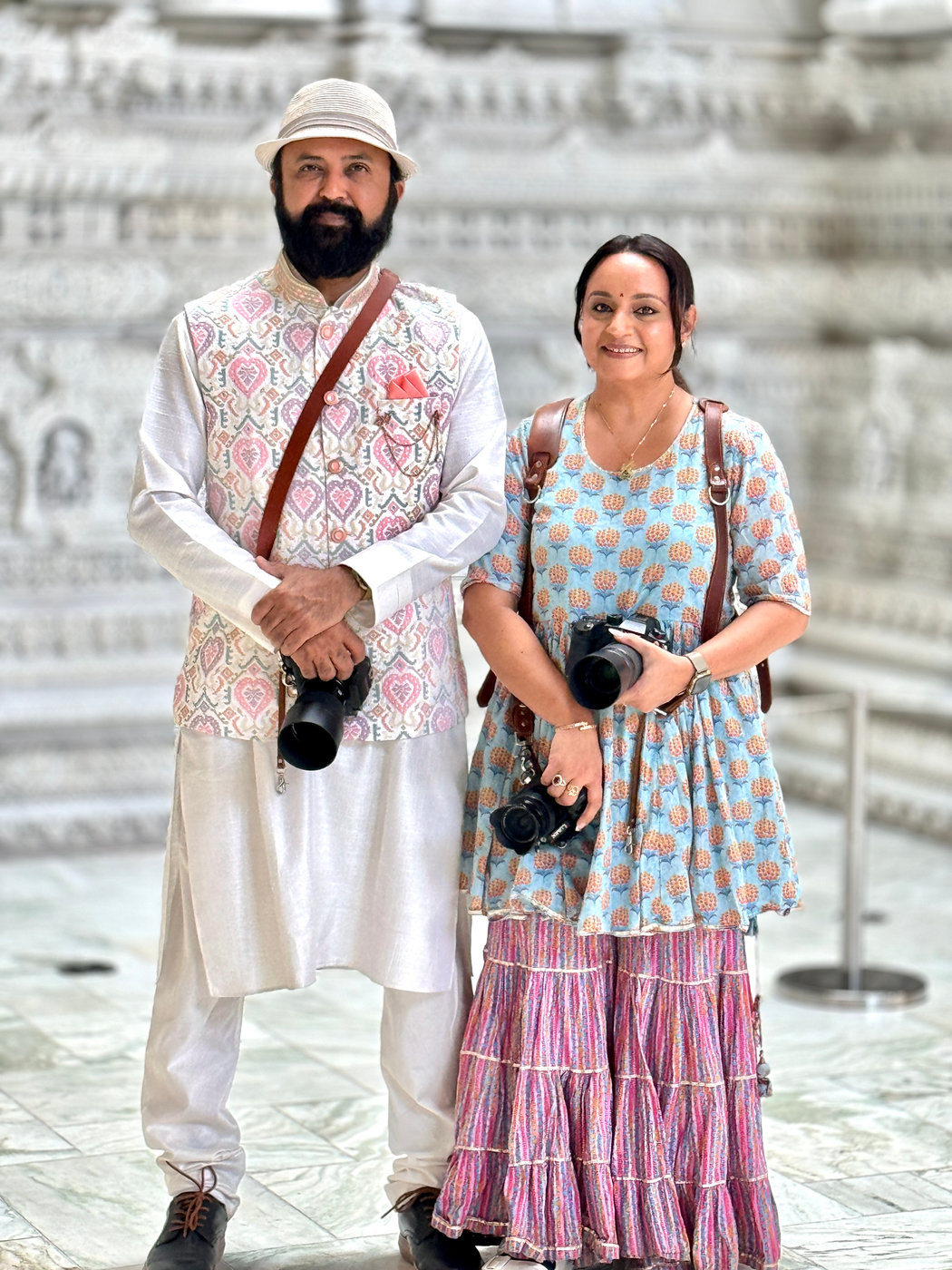 Chirali and Amish Thakkar photographing together, cameras in hand, inside a wedding venue